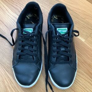 Puma black leather sneakers with patent leather accents.
